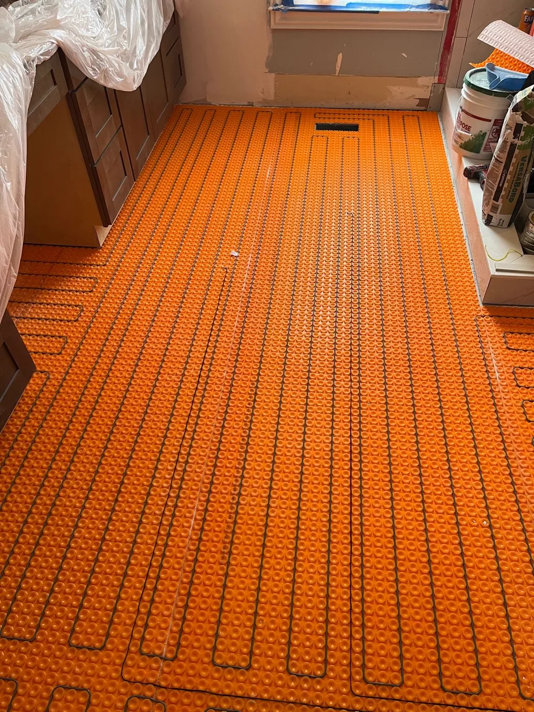Cables de calefacción fijados a la membrana del piso durante la instalación de un sistema de piso radiante, remodelación de baño principal, Metro Atlanta