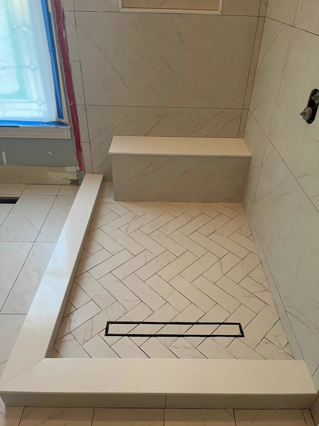 Finished walk-in shower with large-format marble-look tile and a herringbone tile pan, master bathroom remodel, Metro Atlanta