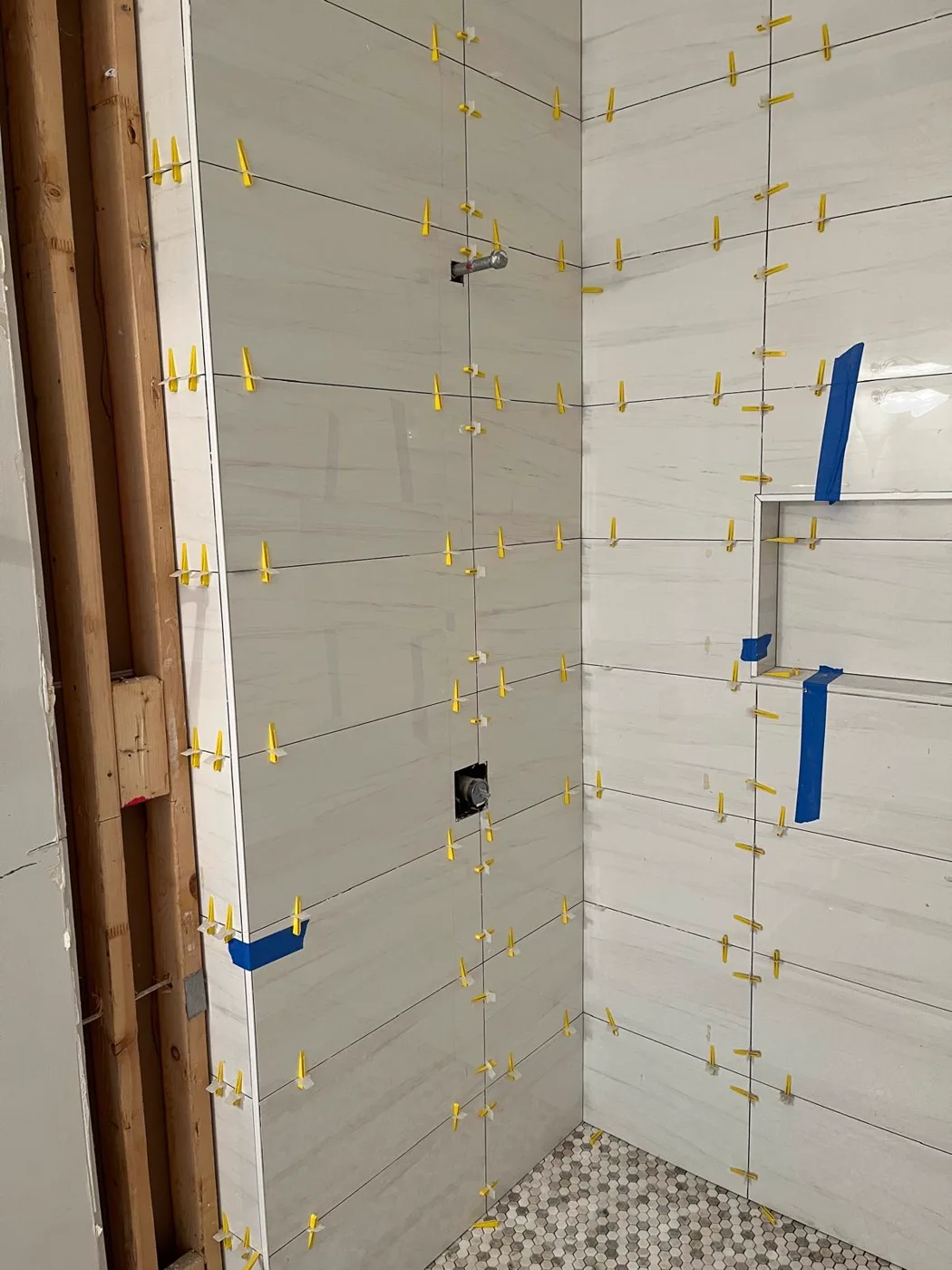 Instalación de azulejo en la pared de la ducha en proceso, con separadores en las juntas, remodelación de baño principal, Metro Atlanta