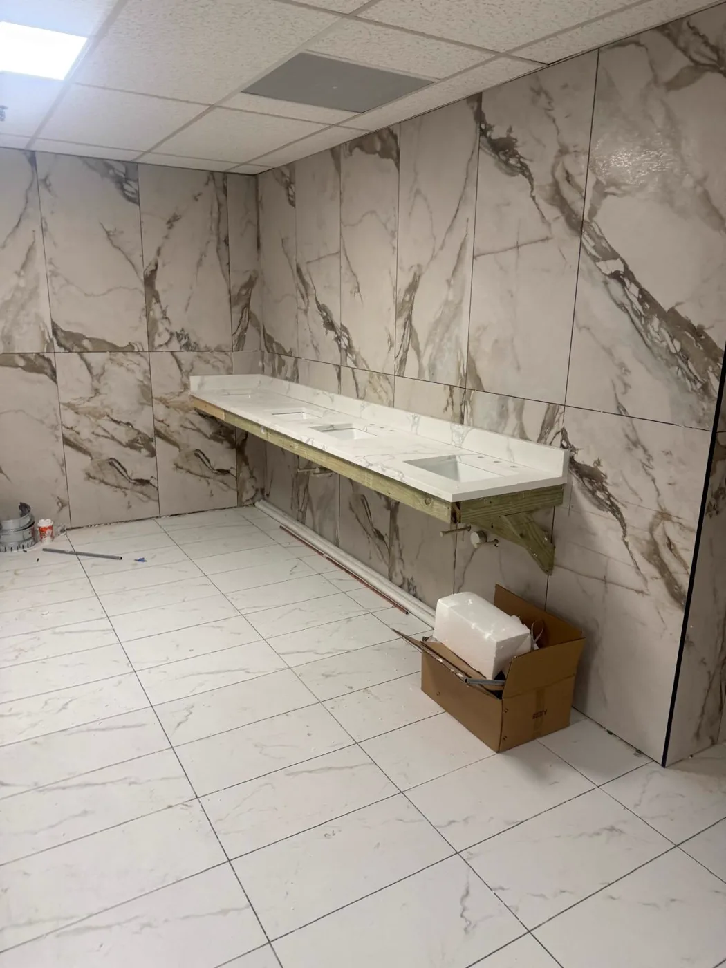 Larga pared de lavabos de mármol en un baño comercial terminado, renovación de local, Metro Atlanta