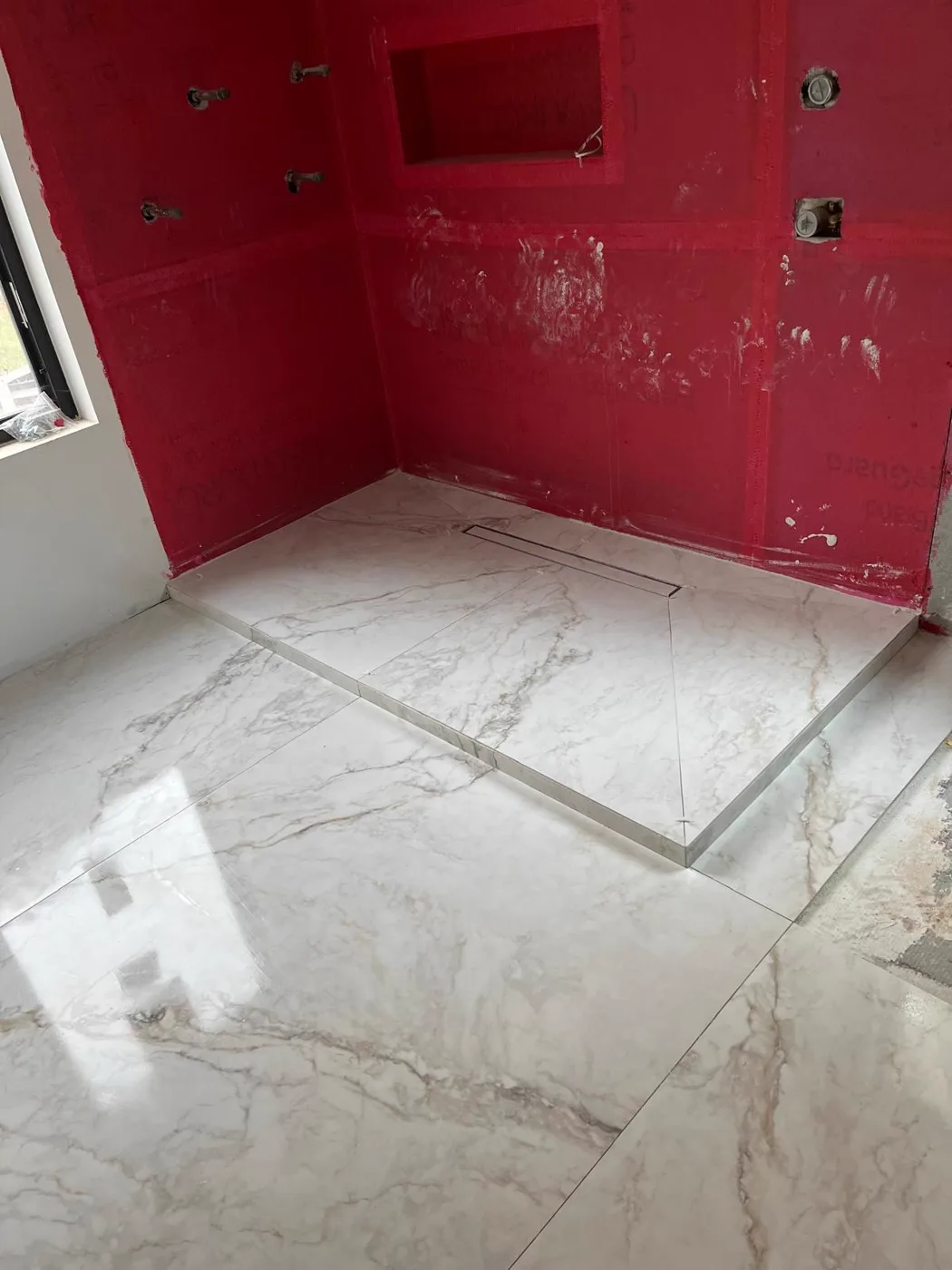 Membrana impermeabilizante roja aplicada en una ducha antes del azulejo, renovación de un local comercial, Metro Atlanta