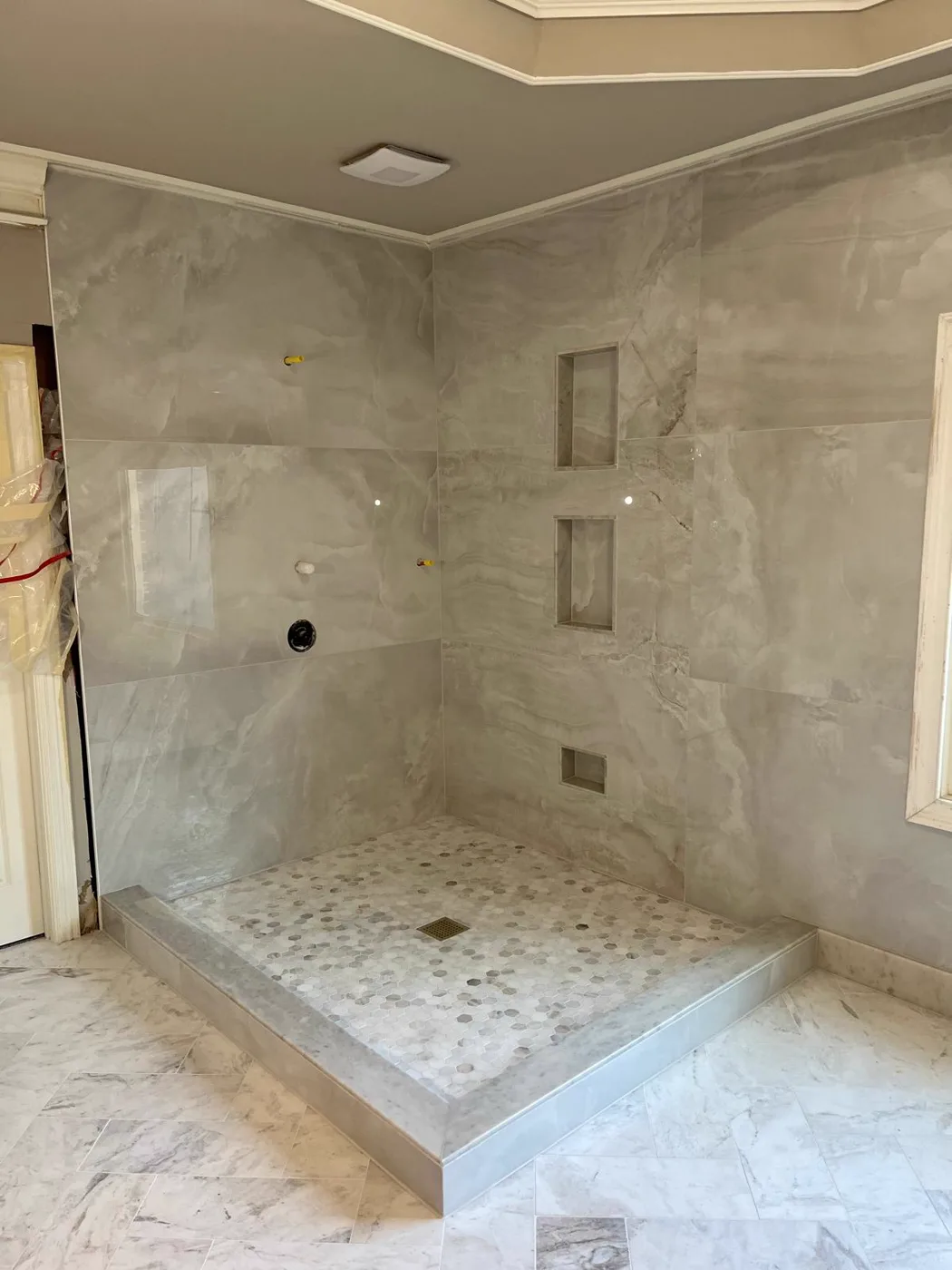 Finished spa shower with marble walls, a tiled niche and a pebble floor, commercial venue renovation, Metro Atlanta
