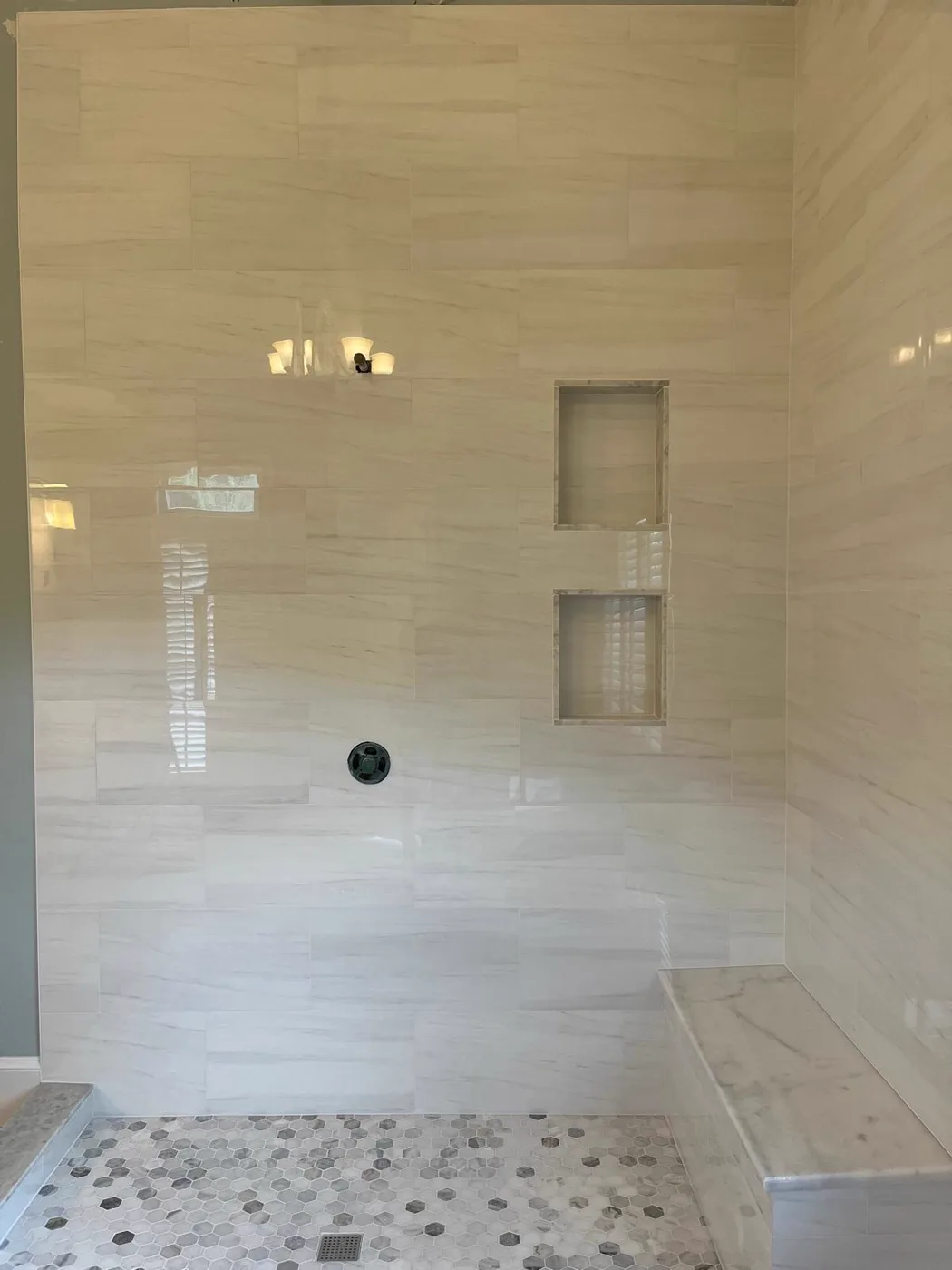 Ducha tipo spa terminada con paredes de mármol y piso de mosaico de piedra, renovación de un local comercial, Metro Atlanta