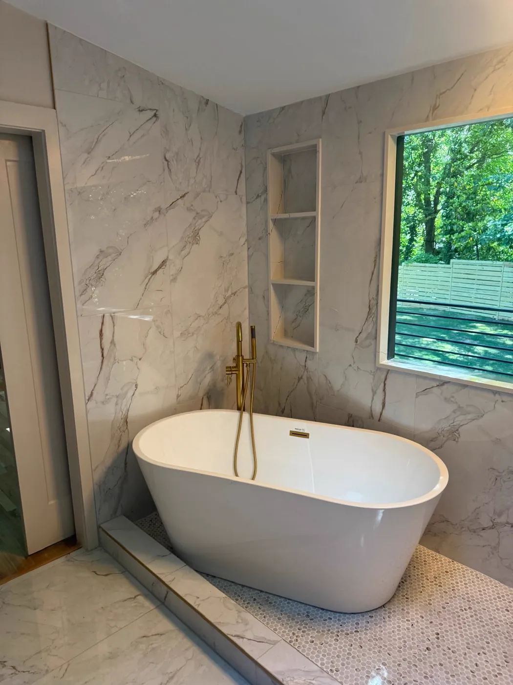 Bañera exenta con llave de piso dorada, paredes tipo mármol y nicho integrado, Metro Atlanta