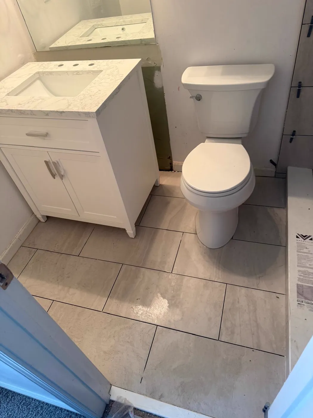 Baño terminado con vanidad blanca, inodoro nuevo y piso de azulejo de formato grande, Metro Atlanta