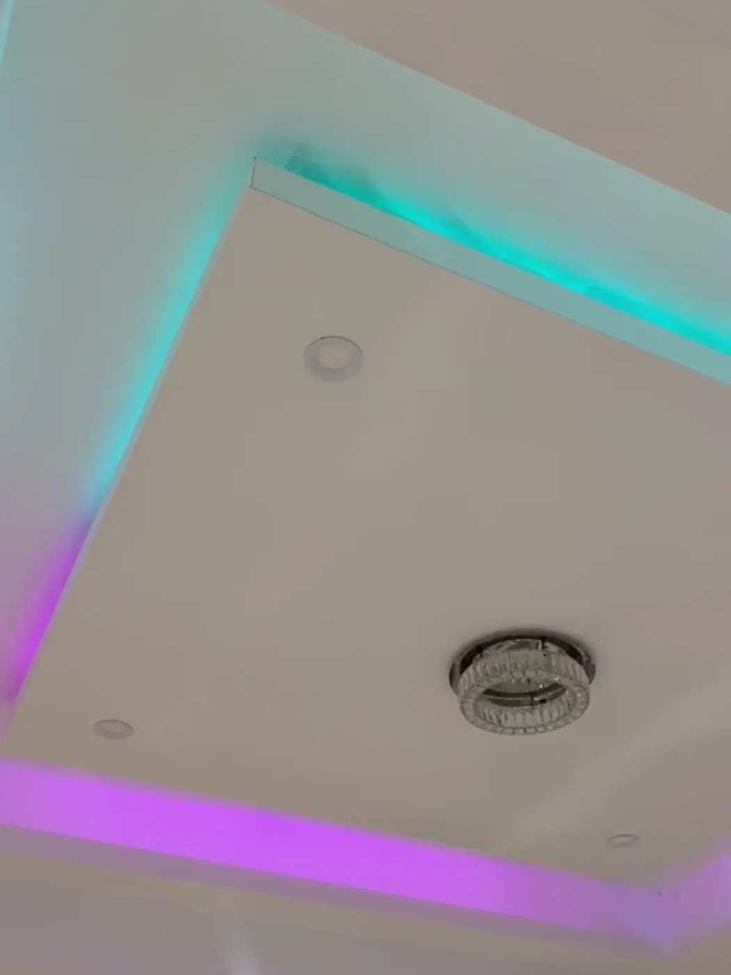 Corner detail of a tray ceiling with concealed LED cove lighting in teal and violet, Metro Atlanta